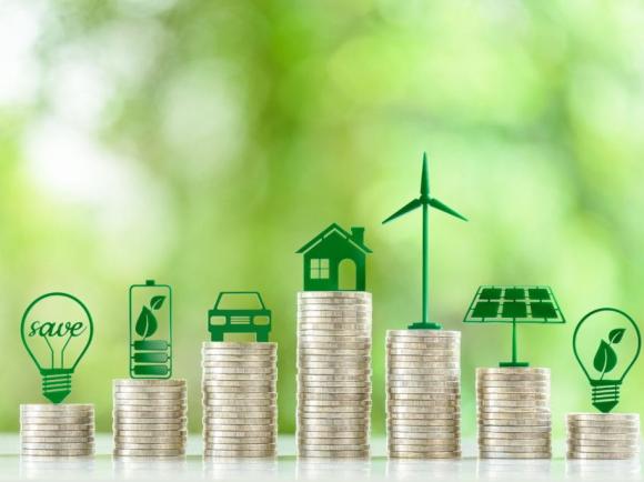 Stacks of coins topped with green icons representing clean energy and sustainability.